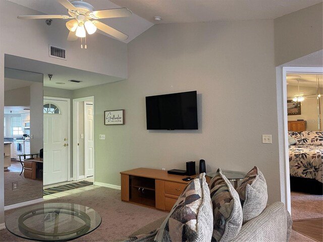 carpeted living room with ceiling fan and vaulted ceiling