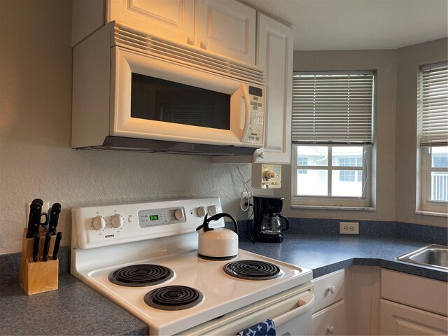 kitchen with a healthy amount of sunlight, white appliances, and white cabinetry