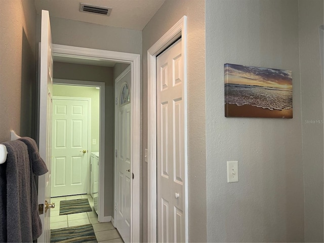 hall featuring washer and clothes dryer and light tile patterned flooring