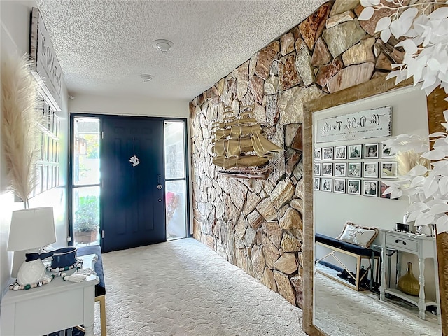 foyer entrance featuring a textured ceiling and carpet