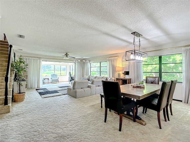 dining room featuring a textured ceiling, ceiling fan, light carpet, and plenty of natural light