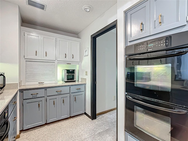 kitchen featuring a textured ceiling, gray cabinetry, and double oven