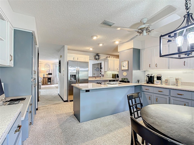 kitchen with a textured ceiling, stainless steel refrigerator with ice dispenser, decorative light fixtures, light carpet, and ceiling fan