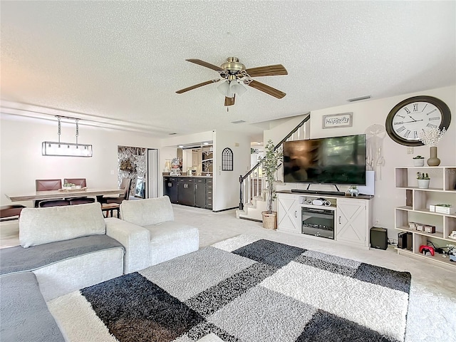 living room with a textured ceiling, ceiling fan, and carpet floors