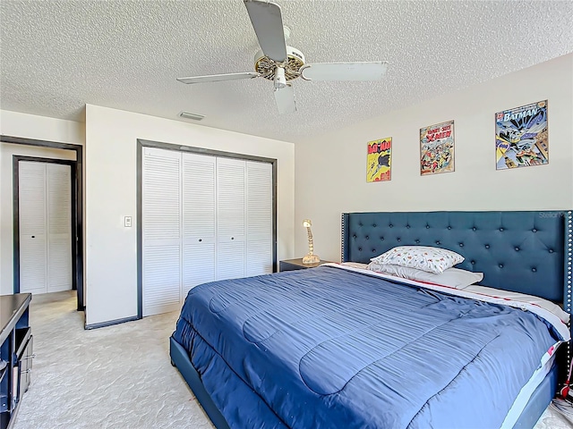 bedroom with ceiling fan, a textured ceiling, a closet, and light carpet