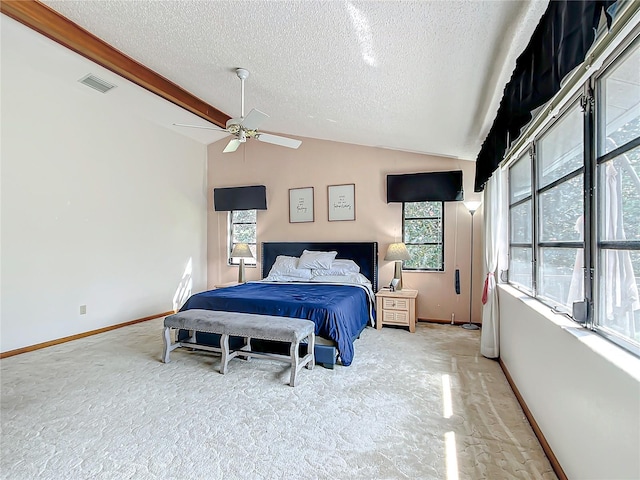 bedroom with a textured ceiling, multiple windows, light carpet, vaulted ceiling with beams, and ceiling fan