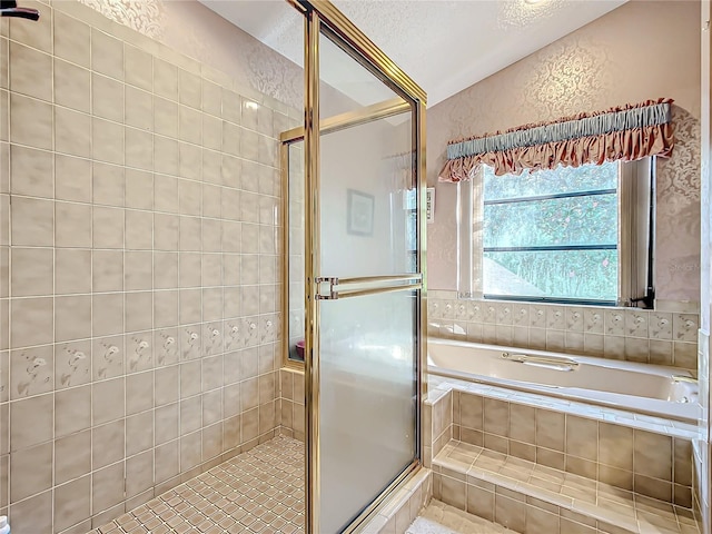 bathroom with a textured ceiling and shower with separate bathtub