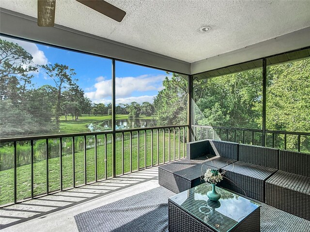 sunroom / solarium featuring ceiling fan and a water view