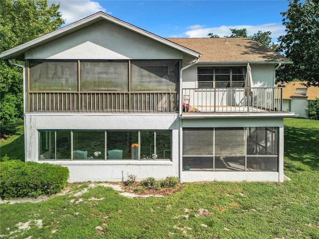 rear view of property with a balcony, a sunroom, and a lawn