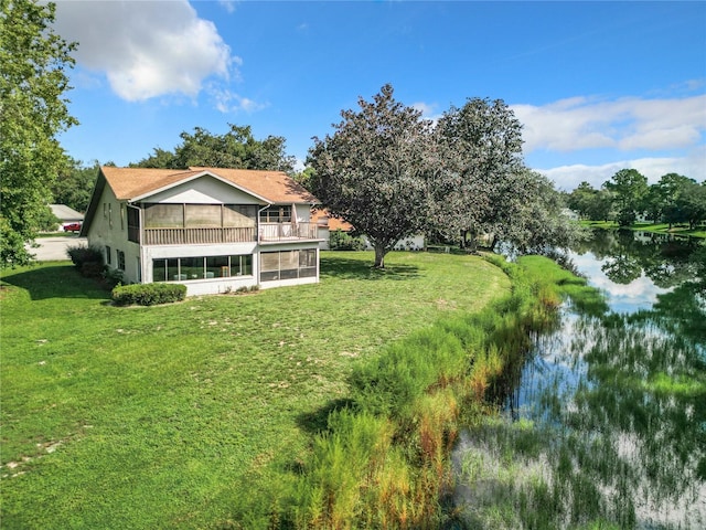 rear view of property with a sunroom, a water view, and a lawn