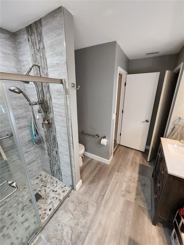 bathroom with walk in shower, wood-type flooring, vanity, and toilet