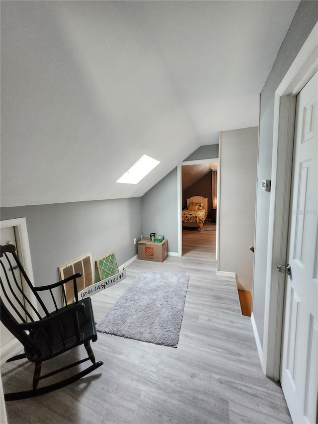 additional living space featuring vaulted ceiling with skylight and light hardwood / wood-style floors