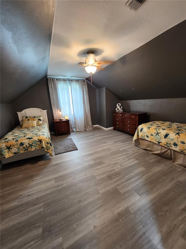 unfurnished bedroom featuring a textured ceiling, lofted ceiling, hardwood / wood-style floors, and ceiling fan