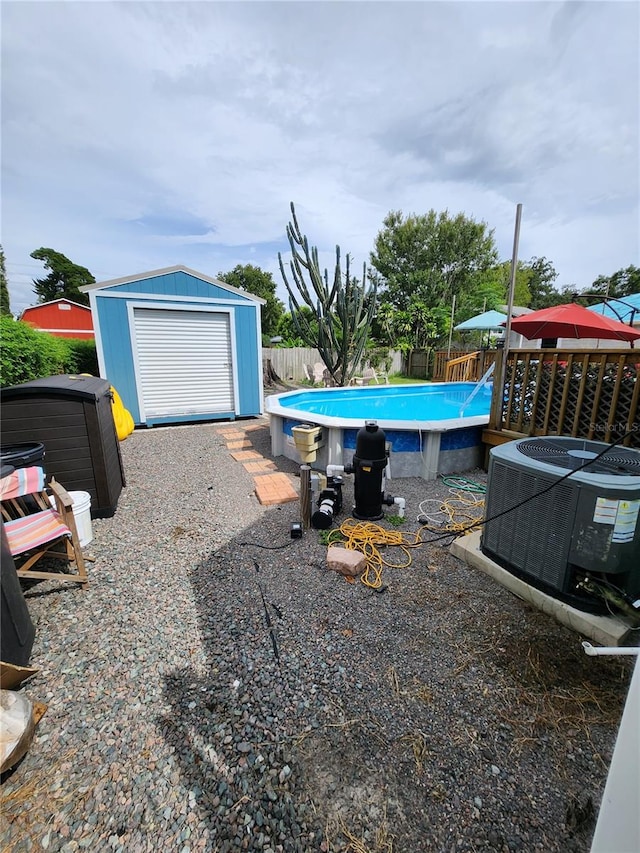 view of yard featuring a fenced in pool, a garage, a storage shed, and central AC