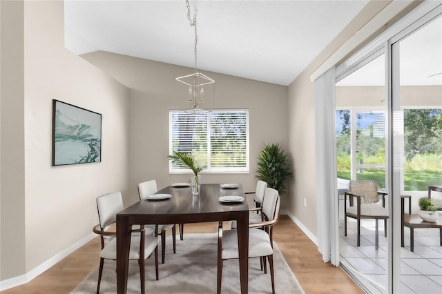 dining room featuring plenty of natural light, light hardwood / wood-style flooring, and vaulted ceiling