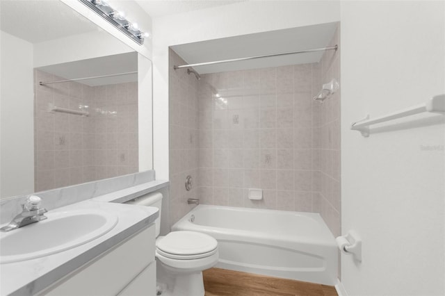 full bathroom featuring hardwood / wood-style floors, vanity, tiled shower / bath, toilet, and a textured ceiling