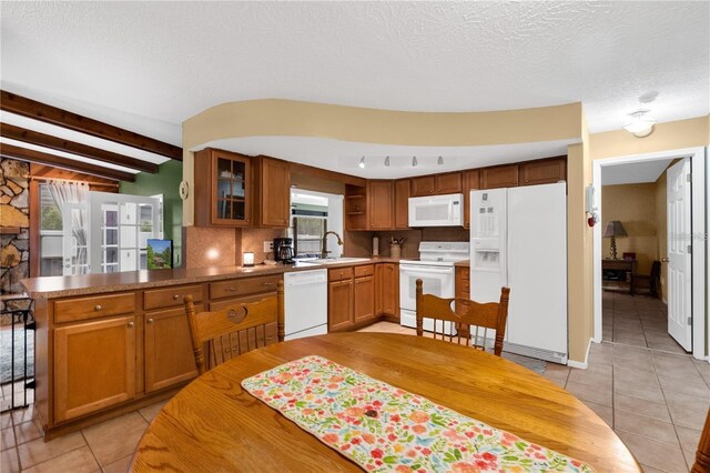 kitchen featuring beamed ceiling, white appliances, kitchen peninsula, and a healthy amount of sunlight