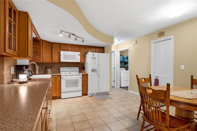 kitchen featuring white appliances, a textured ceiling, light tile patterned floors, sink, and washer / dryer