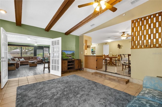 living room with beamed ceiling, light tile patterned floors, ceiling fan, and a textured ceiling