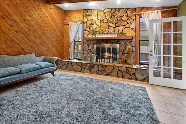 tiled living room featuring wood walls and a stone fireplace