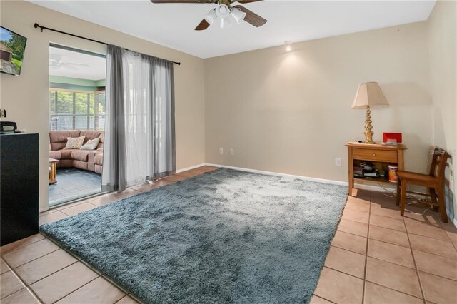 living area with light tile patterned floors and ceiling fan