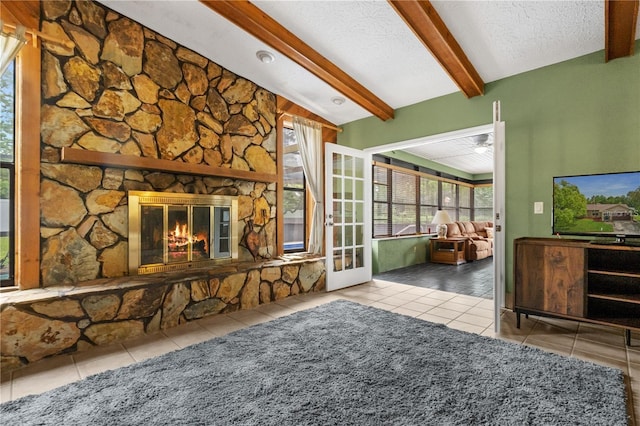 tiled living room with a fireplace, a textured ceiling, ceiling fan, and vaulted ceiling with beams