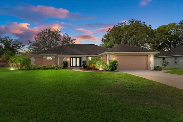 ranch-style house featuring a garage, french doors, and a lawn