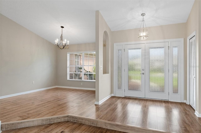 foyer entrance featuring french doors, hardwood / wood-style floors, a wealth of natural light, and a chandelier