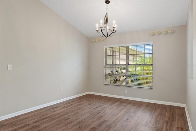 spare room with hardwood / wood-style floors, lofted ceiling, and a notable chandelier