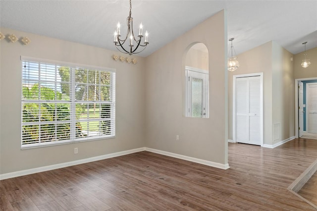 unfurnished room featuring dark hardwood / wood-style floors, a chandelier, and vaulted ceiling