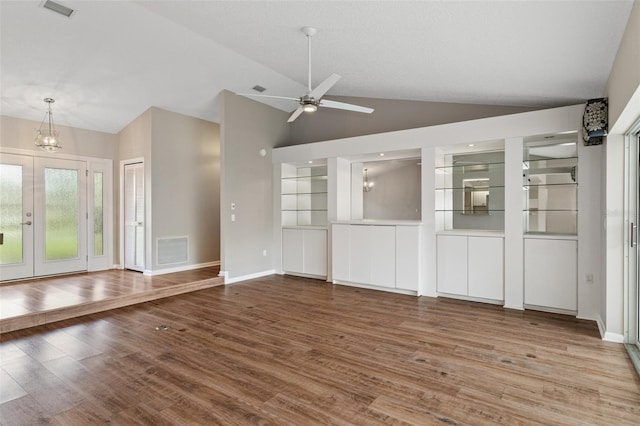 unfurnished living room with lofted ceiling, ceiling fan with notable chandelier, and hardwood / wood-style flooring