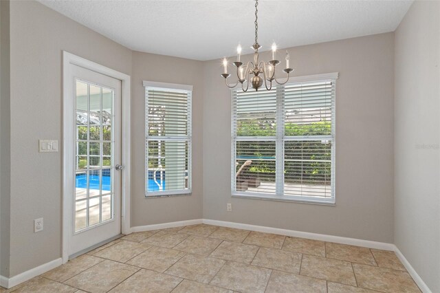 unfurnished dining area with a textured ceiling and an inviting chandelier