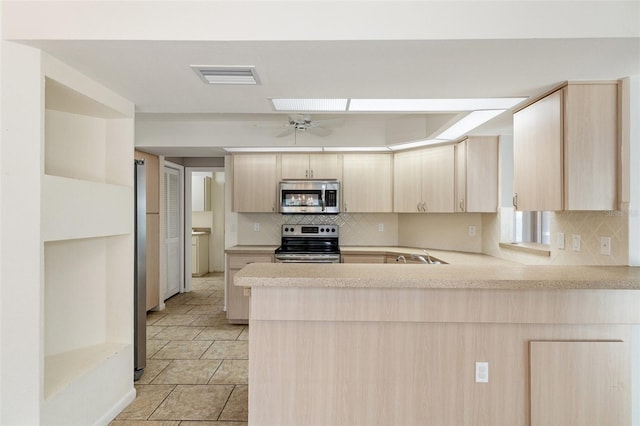 kitchen with light brown cabinets, stainless steel appliances, backsplash, kitchen peninsula, and ceiling fan