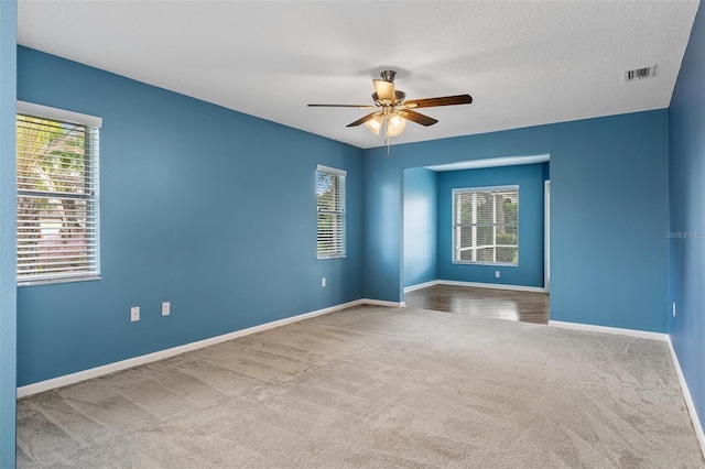 carpeted spare room featuring ceiling fan and a textured ceiling