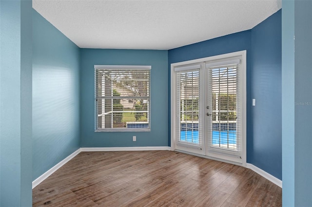 spare room with french doors, a textured ceiling, and wood-type flooring