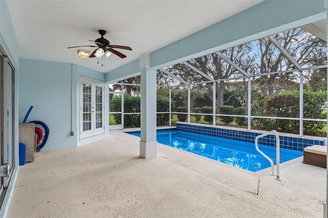 view of swimming pool with ceiling fan, glass enclosure, and a patio