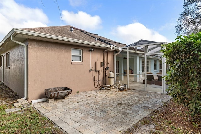 back of property featuring glass enclosure and a patio