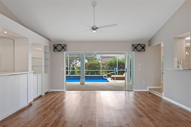 interior space with hardwood / wood-style floors, ceiling fan, a textured ceiling, vaulted ceiling, and built in shelves