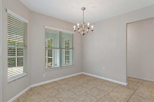 unfurnished room with light tile patterned flooring, a chandelier, and a textured ceiling