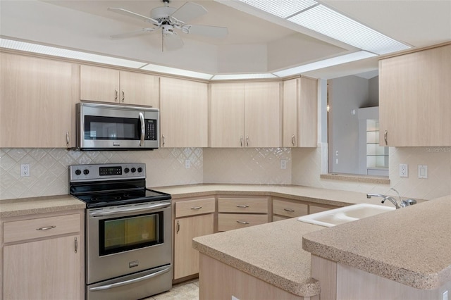 kitchen with sink, light brown cabinets, appliances with stainless steel finishes, and kitchen peninsula