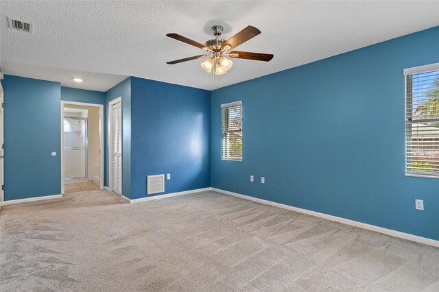 carpeted empty room with ceiling fan and a textured ceiling