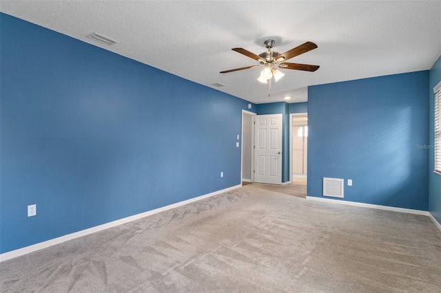 carpeted spare room with a textured ceiling and ceiling fan