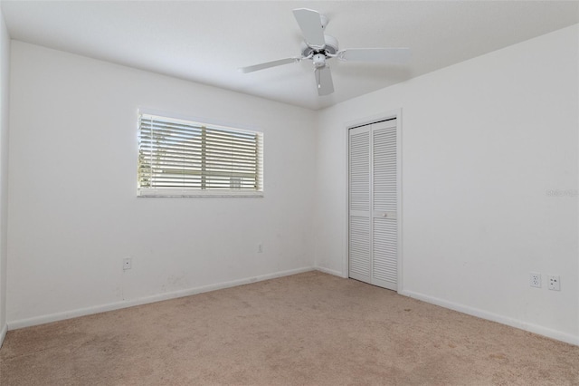 unfurnished bedroom featuring ceiling fan, a closet, and light carpet