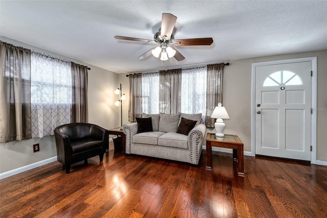 living room featuring dark hardwood / wood-style flooring, ceiling fan, and a textured ceiling