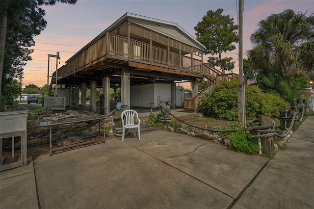 14904 Old Dixie Hwy, Hudson, FL 34667 - back of property at dusk with a wooden deck, stairway, and a patio