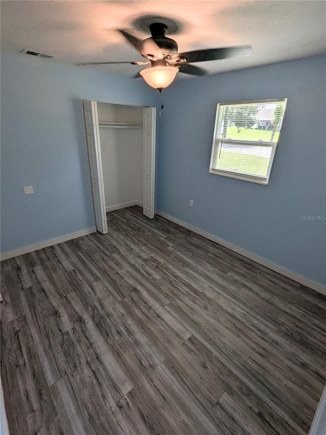 unfurnished bedroom with ceiling fan, dark wood-type flooring, and a closet