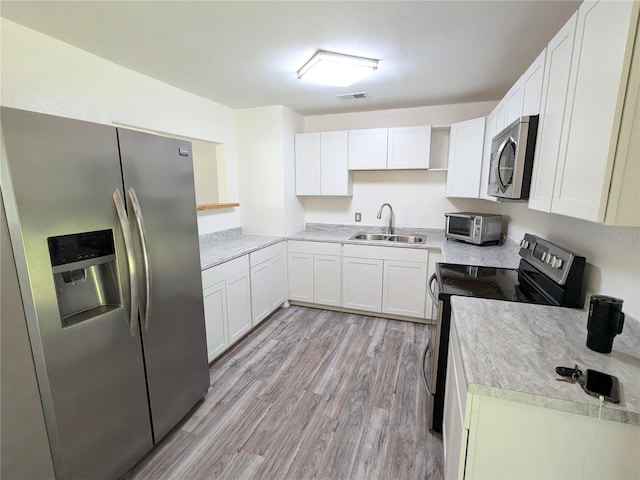 kitchen featuring sink, stainless steel appliances, white cabinetry, and light hardwood / wood-style flooring