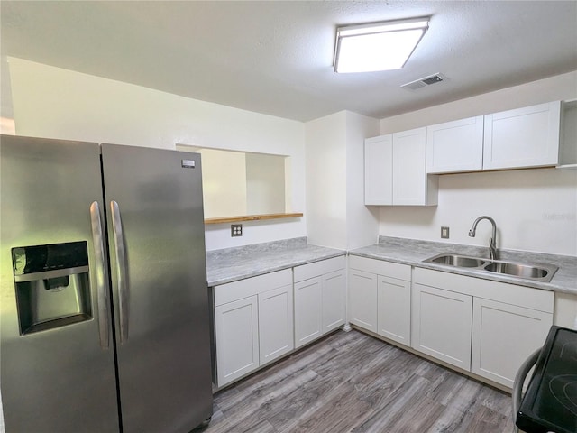 kitchen with a textured ceiling, sink, white cabinets, light hardwood / wood-style flooring, and stainless steel appliances