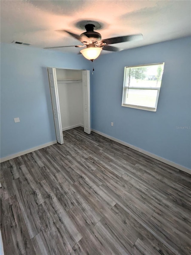 unfurnished bedroom with ceiling fan, dark hardwood / wood-style floors, and a closet