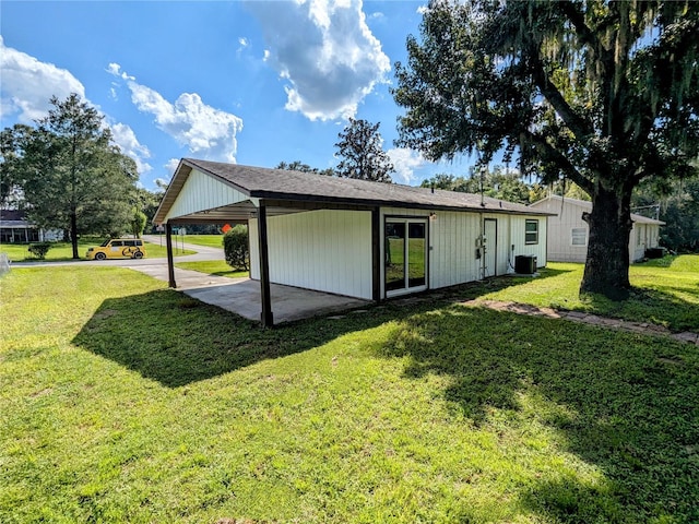 rear view of house featuring cooling unit, a carport, and a yard